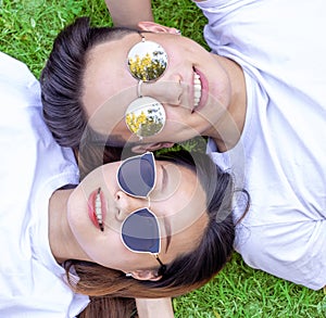 Young boy and girl with sunglasses lying down on grass and smilin