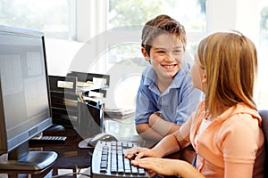 Young boy and girl using computer at home