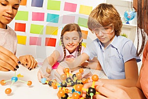 Young boy and girls assembling molecule model