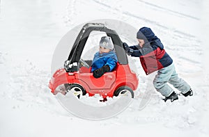 Young Boy Gives a Push to his Brother's Car Stuck in the Snow photo