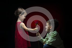 Young boy giving a rose to a little girl