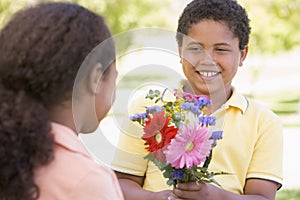 Young boy giving young girl flowers