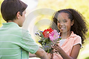 Young boy giving young girl flowers and smiling