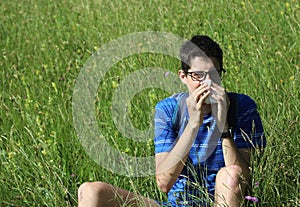 Young boy with glasses blowing his nose because of allergy in th