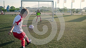 Young boy goalie in football uniform misses shot