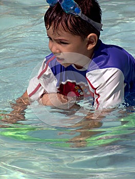 Young boy with goggles on his head in the pool