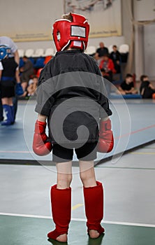 Young boy sportsmen fighter in a gloves and a protective headgear before going into the ring