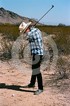 Young boy golfing in the desert