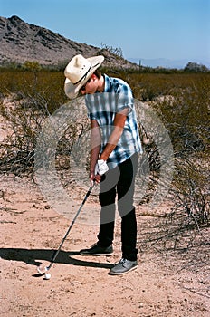 Young boy golfing in the desert