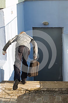 Young boy in a gray jacket with a briefcase falls from stairs edge down