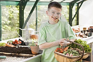 Young boy in greenhouse holding basket