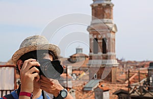 Young boy with hat takes picutres with his digital camera in Ven