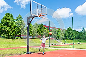 Young boy having fun playing basketball outdoors.nice,cool caucasian alone player playing basketball outdoors