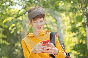 A young boy is having a video call outdoors, holding a smartphone in his hands.