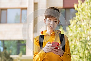 A young boy is having a video call outdoors, holding a smartphone in his hands.