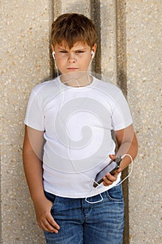 Young boy in headphones with smartphone listens to music in the park