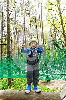 Young boy in helmet walks by rope