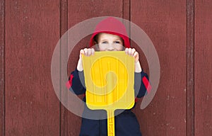 Young boy hides behind toy shovel