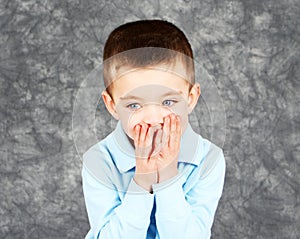 Young boy hiding face in hands
