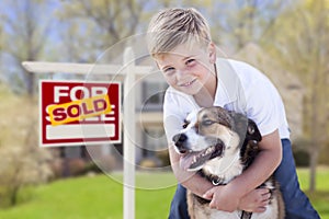 Young Boy and His Dog in Front of Sold For Sale Sign and House