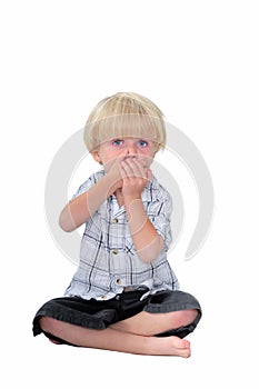 Young boy with his hands over his mouth and white background