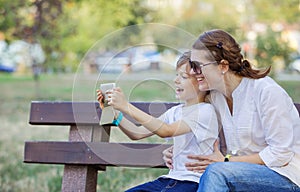 Young boy and his mother using smartphone to take selfie