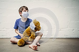 Young boy and his teddy bear wearing protective masks