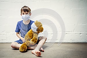 Young boy and his teddy bear wearing protective masks