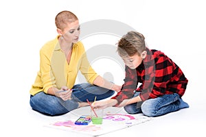 Young boy and his therapist in child occupational therapy session painting with watercolors. Child art therapy concept.