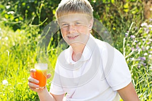 Young boy is holding glass with carrot juice