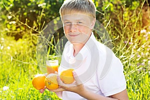 Young boy is holding glass with orange juice and