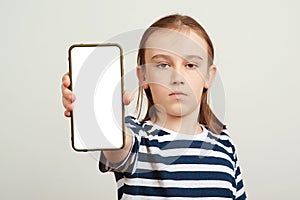 Young boy holding mobile phone with white blank screen in hand. Gadget with empty free space for mock up