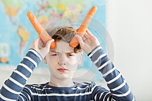 Young boy holding two carrots for horns