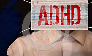 Young boy holds ADHD text written on sheet of paper. ADHD is Attention deficit hyperactivity disorder