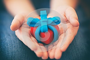 Young boy holds gift wrapped with blue ribbon