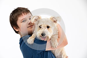 Young boy holds his dog in his arms. Subject isolated from the background.
