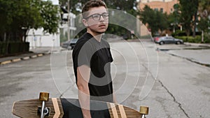 A young boy holds his skateboard