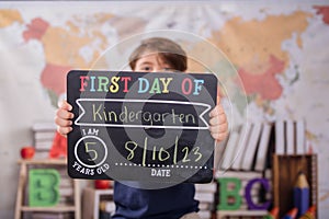 a young boy holds up a chalk board sign that says first day of kindergarten