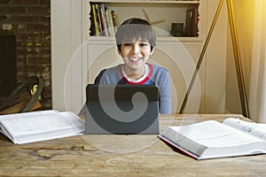 Young Boy is Home Schooled During Pandemic - Concept Learning at Home - Small Child - Technology photo