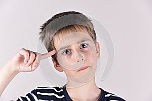 Young boy with the index finger on his head