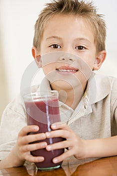 Young boy indoors drinking juice