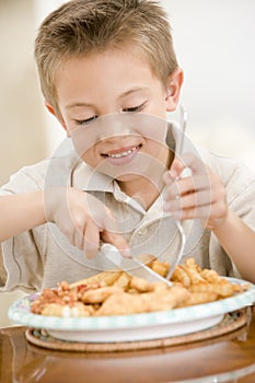 Young boy indoors eating fish and chips