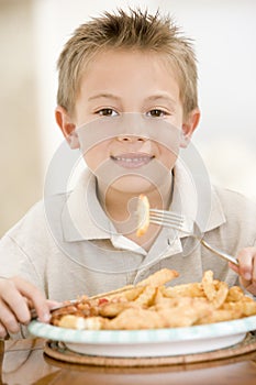 Young boy indoors eating fish and chips