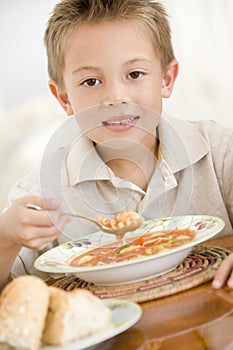 Young boy indoors eating soup