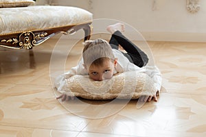 A young boy is indulging on the floor. Lies on a pillow