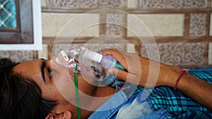 Young boy infected with Covid 19 disease. Patient inhaling oxygen wearing mask with liquid Oxygen flow