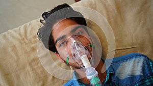 Young boy infected with Covid 19 disease. Patient inhaling oxygen wearing mask with liquid Oxygen flow