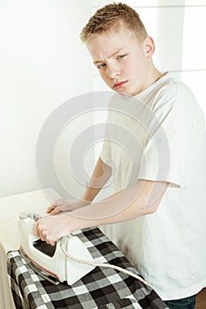 Young Boy Ironing Shirt and Looking Grumpy