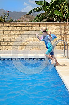 Young boy jumping into pool