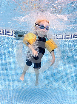 Young boy jumping into a swimming pool